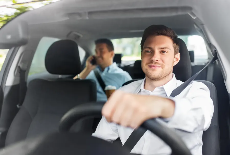 Driver and rear passenger travelling in a car, both wearing seat belts