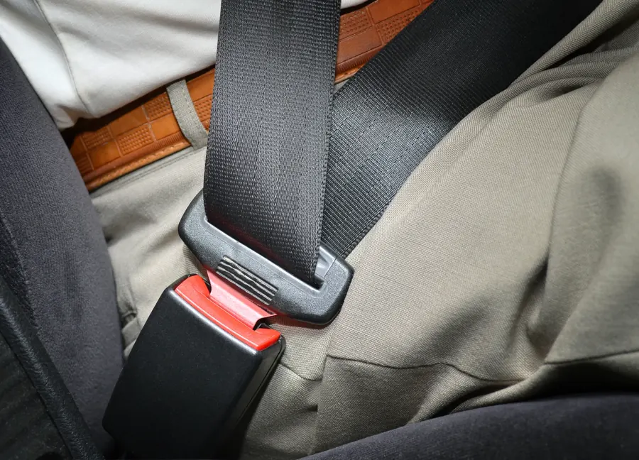 Fastened seat belt across an occupant with the buckle engaged at the seat base