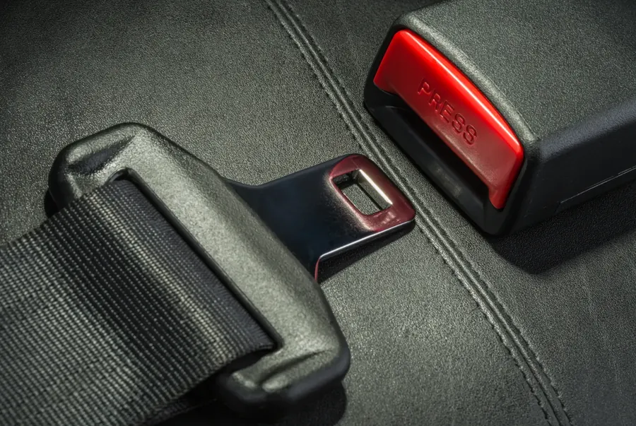 Seat belt latch plate and buckle receiver photographed on a dark leather seat