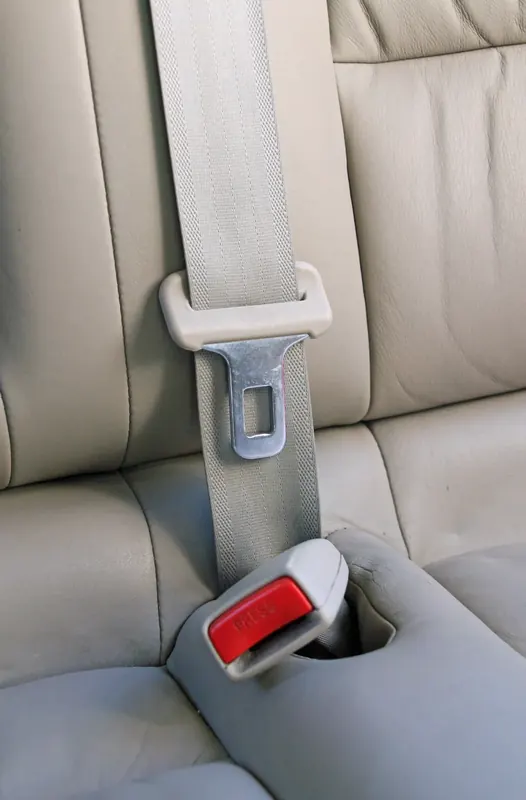 Light grey three-point seat belt fitted to a leather rear seat with the buckle in view