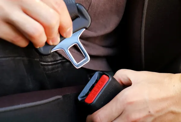 Hands engaging a seat belt latch plate into a buckle